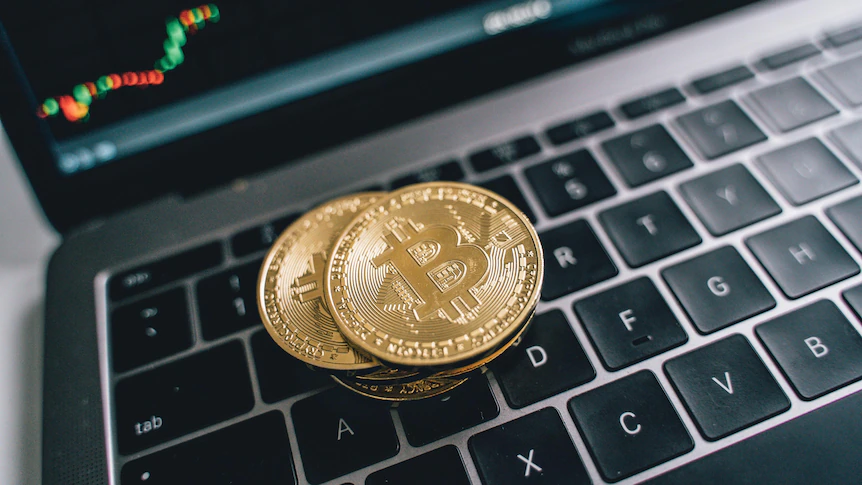 Three coins with the Bitcoin symbol sit on a laptop keyboard.
